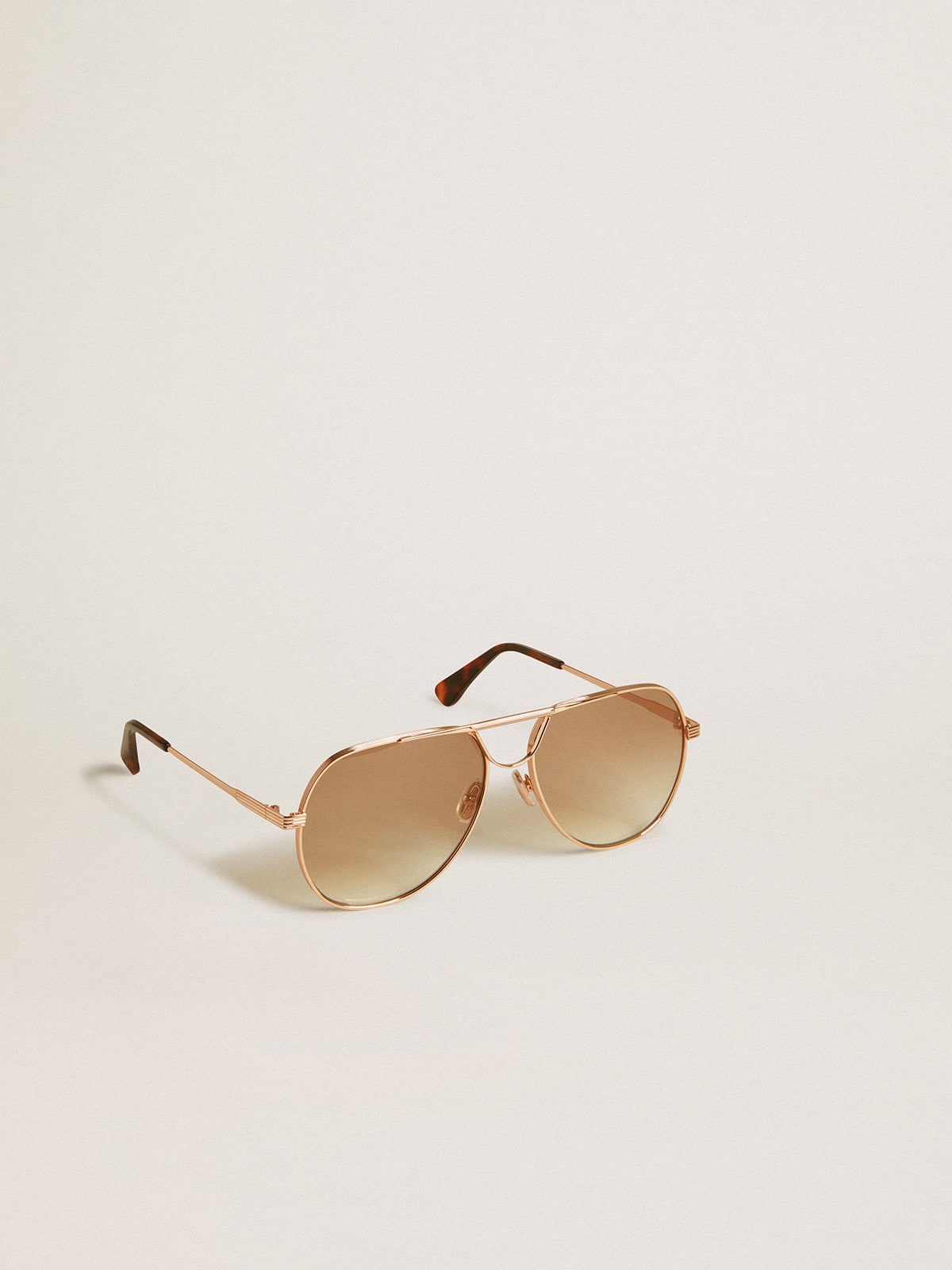 Aviator style sunglasses with rose-gold frame and honey-colored lenses| Golden Goose